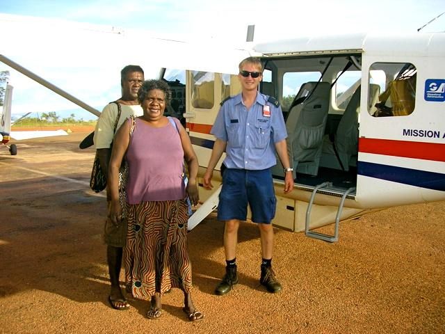 Three people standing in front of a mission airplane