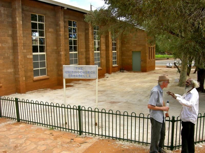 Two men standing in front of a building with a sign that says 