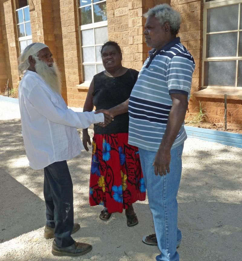 A man in a striped shirt shakes hands with a woman in a red skirt