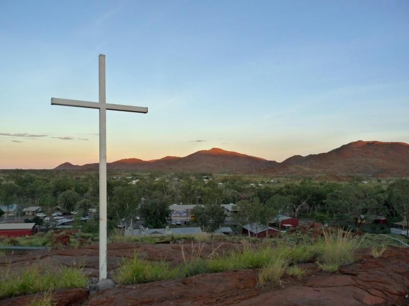 A cross in the middle of a field with mountains in the background