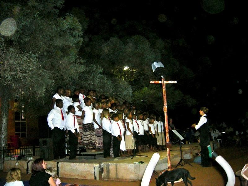 A group of people singing in front of a cross