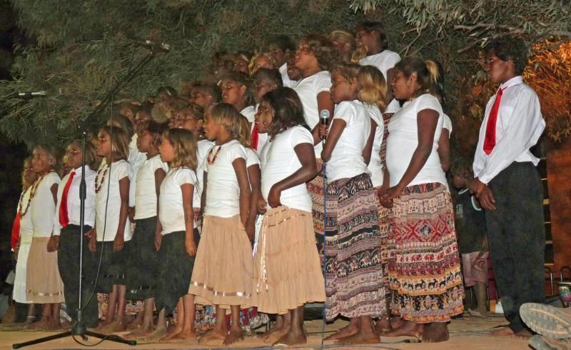 A large group of children are singing on a stage