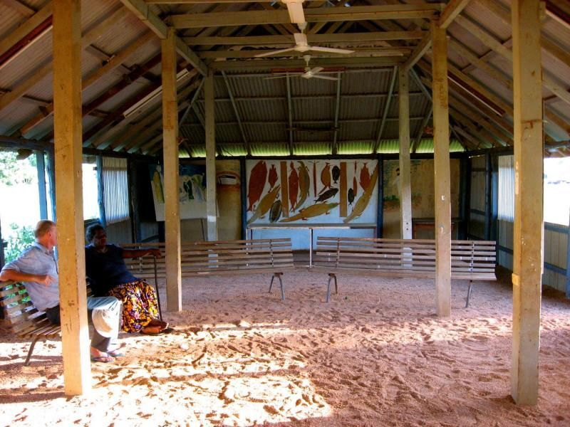 A man sits on a bench in front of a sign that says adieu