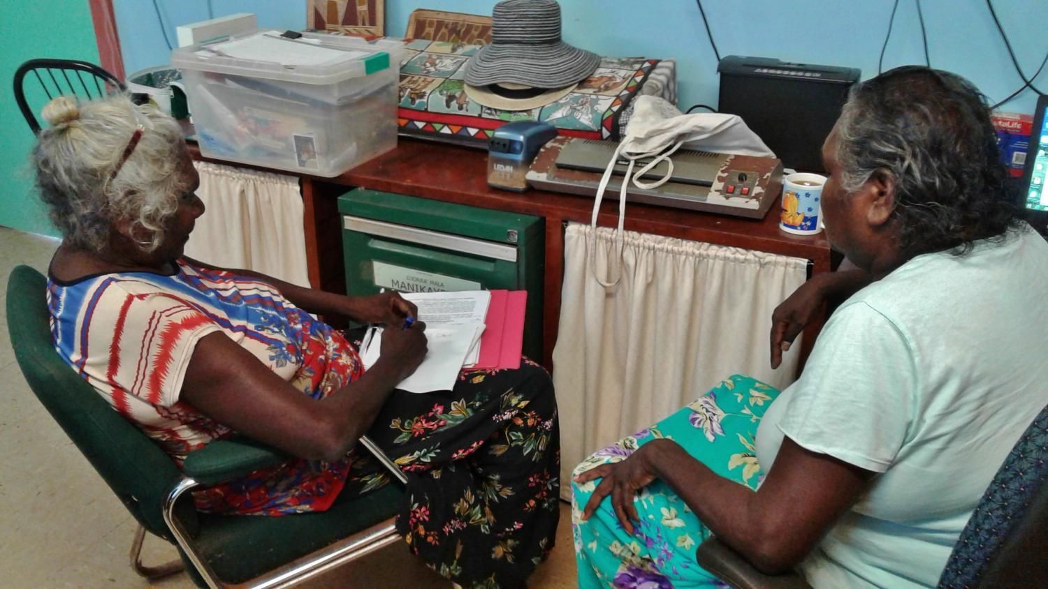 Two women are sitting in chairs talking to each other in a room.