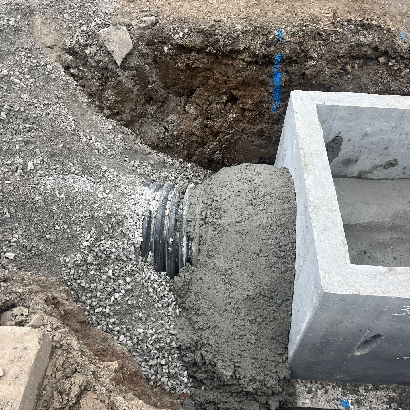 A pile of concrete is being poured into a hole in the ground.