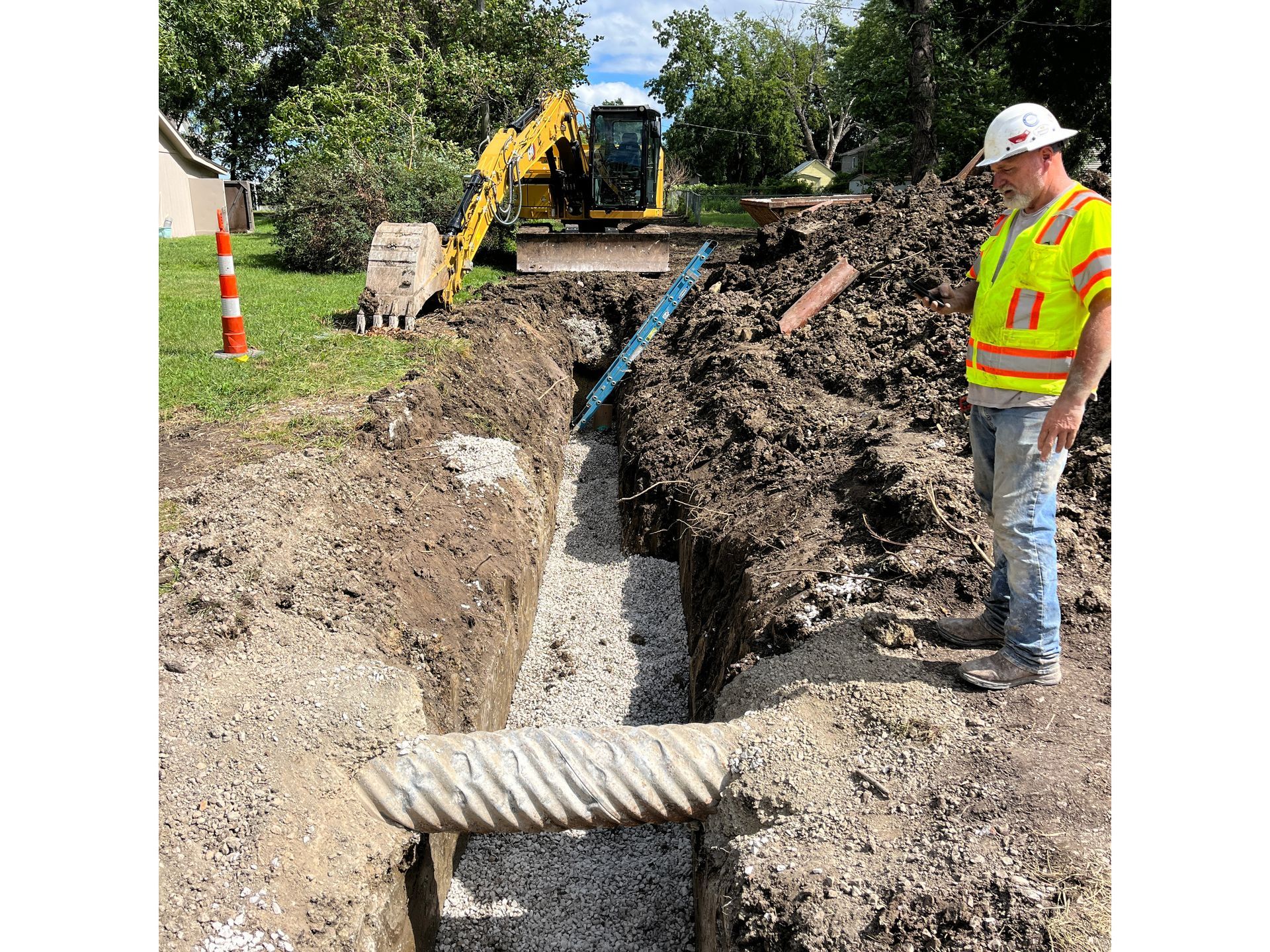 A construction worker is standing in a trench next to a bulldozer.