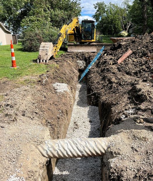 A yellow excavator is digging a trench in the dirt.