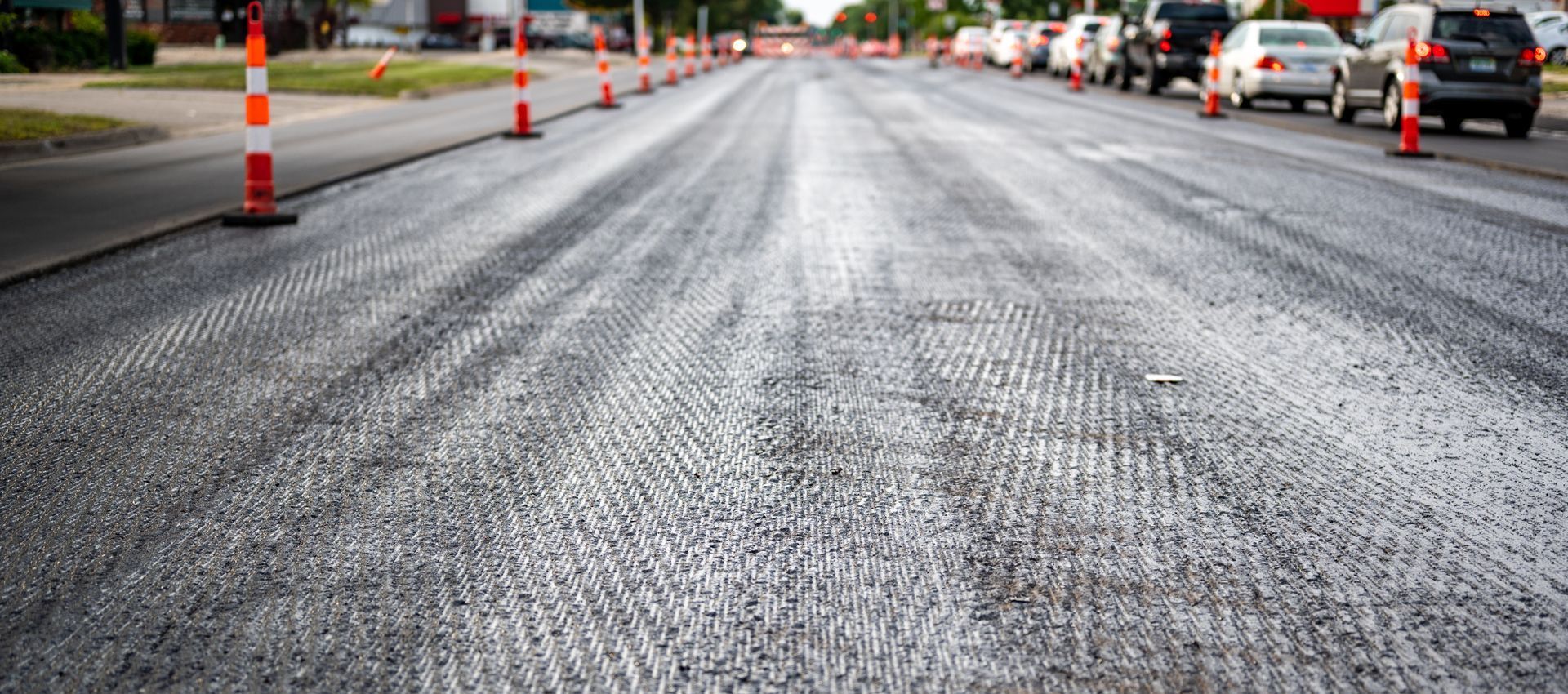 A row of orange and white cones are lined up on the side of a road.