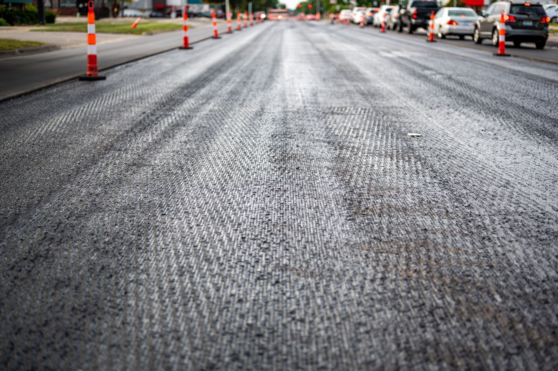 A row of traffic cones are lined up on the side of a road.