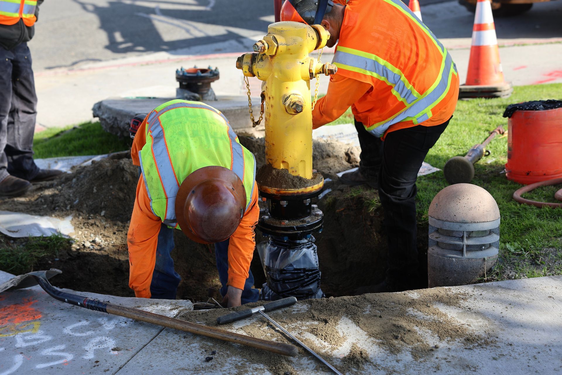 Two construction workers are working on a yellow fire hydrant
