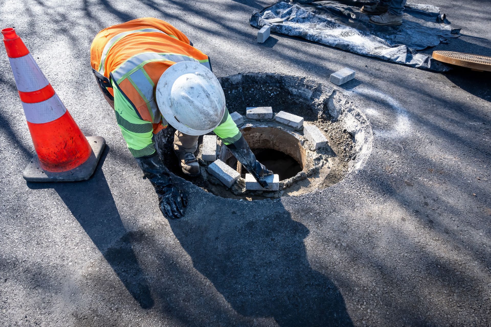 A manhole cover is being repaired by a construction worker.