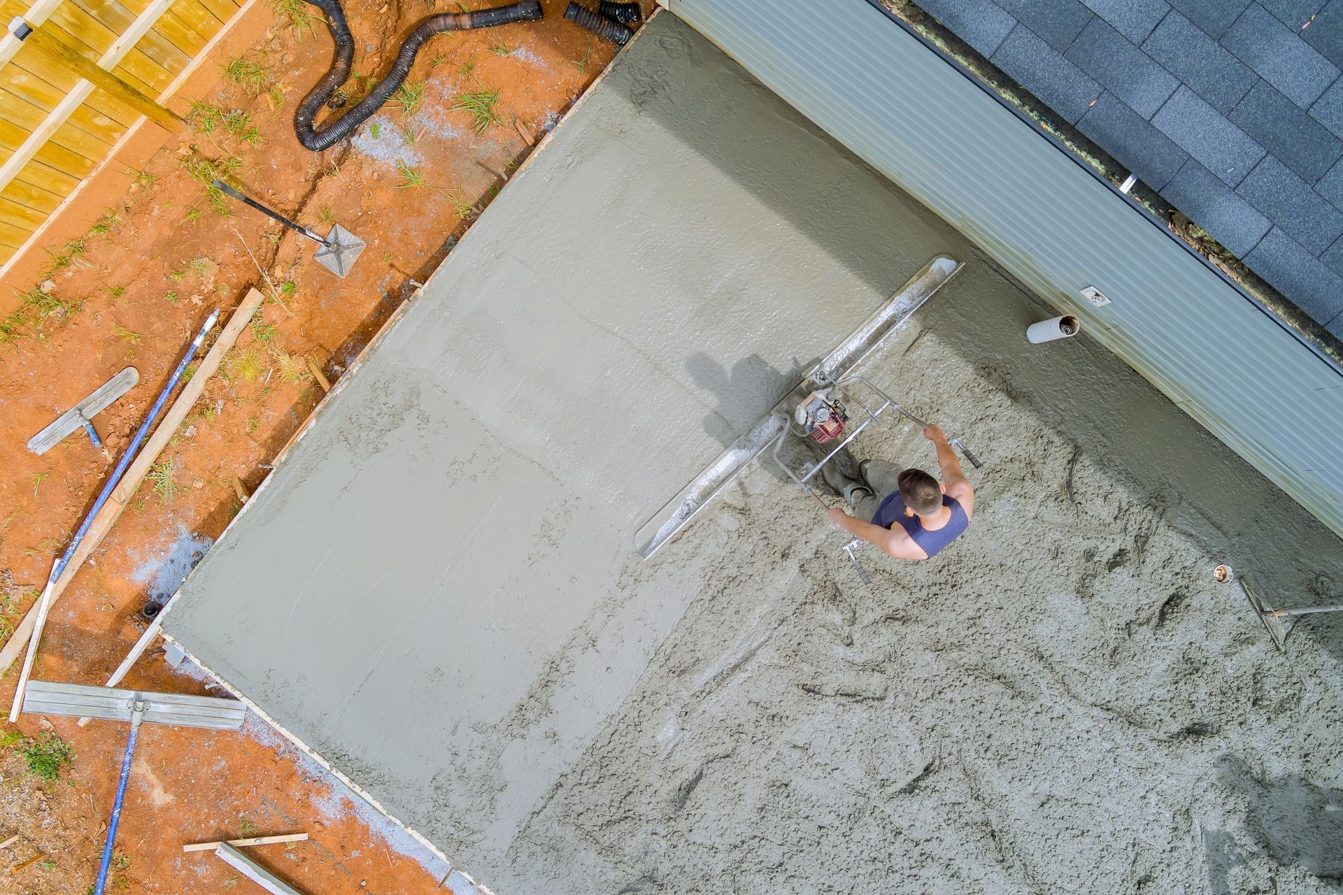 An aerial view of a man laying concrete on a construction site.
