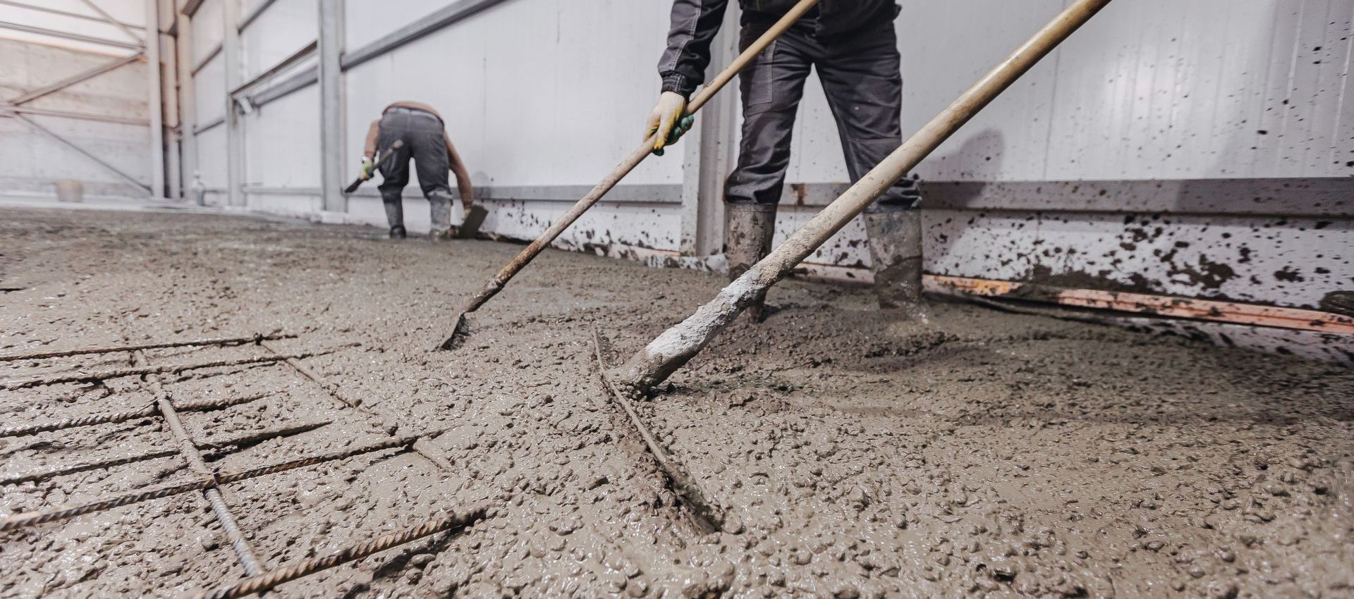 A man is raking a concrete floor with a rake.