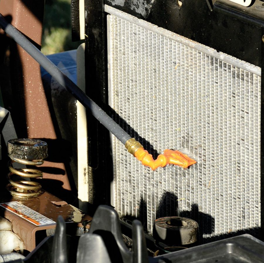 A row of orange string trimmers hangs on a wall rack in a retail store.