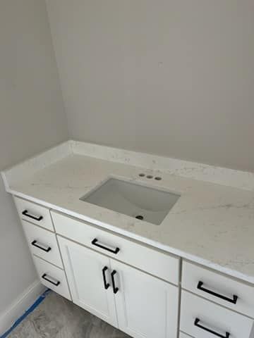 White bathroom vanity with a marble-look countertop and black hardware.