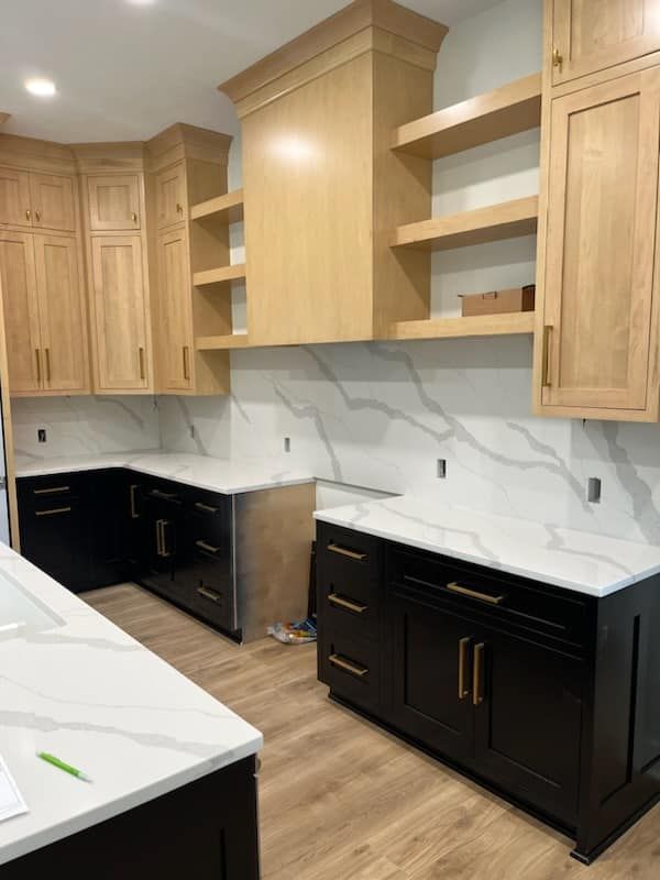 Kitchen remodel: Light wood cabinets, black base cabinets, white countertops, marble backsplash.