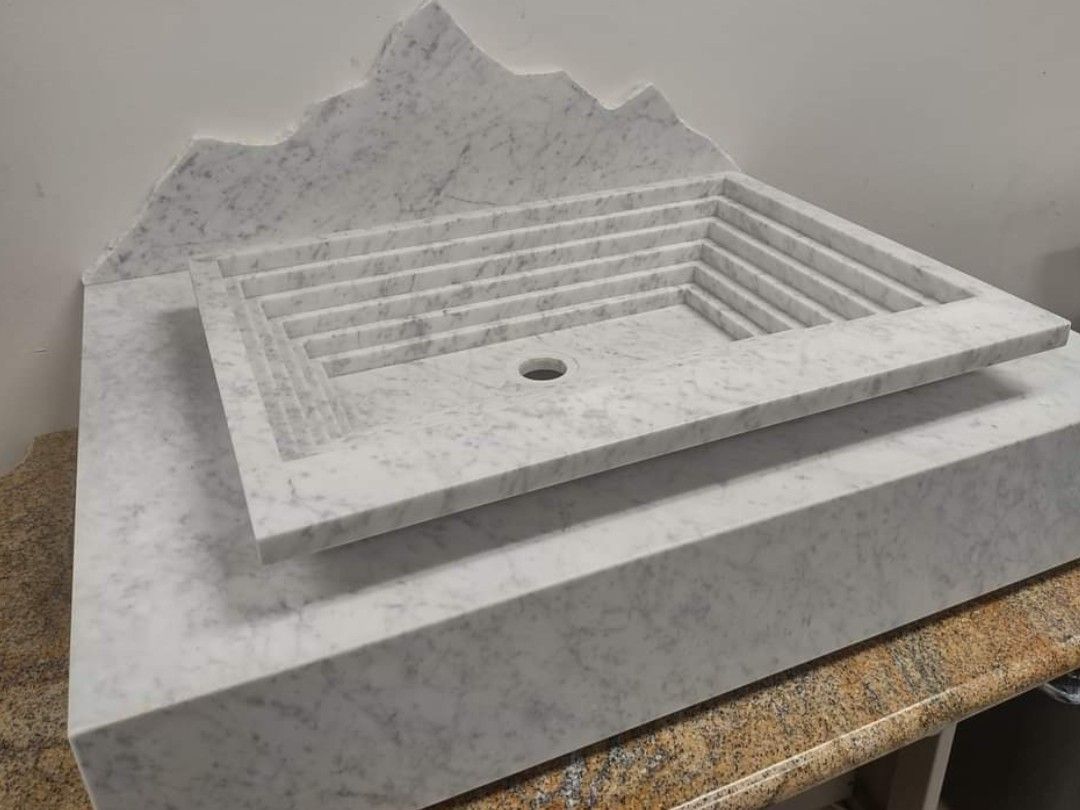 White marble sink with stepped basin and mountain-shaped backsplash.