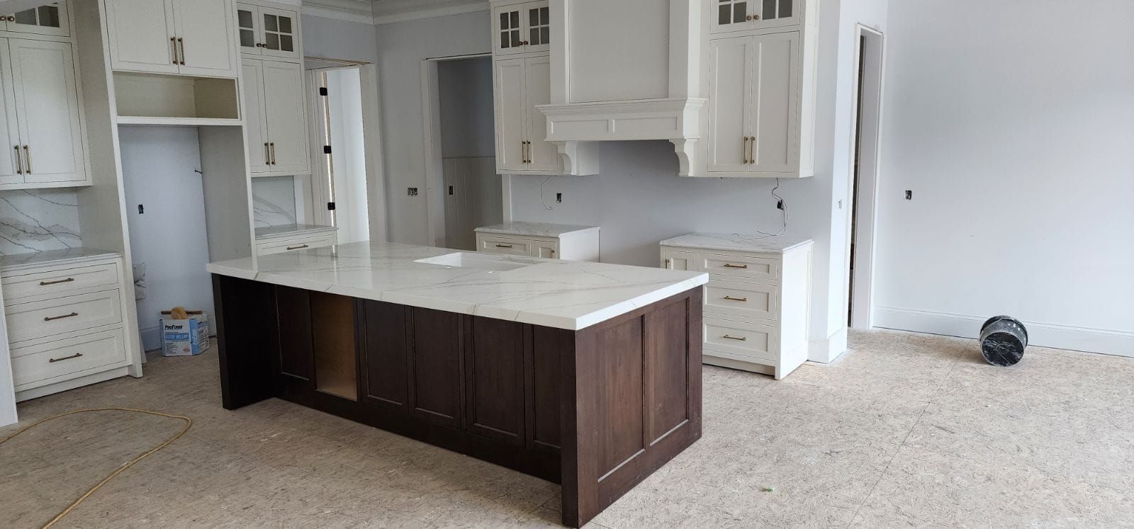 Newly built kitchen with white cabinets, a dark wood island, and speckled flooring.
