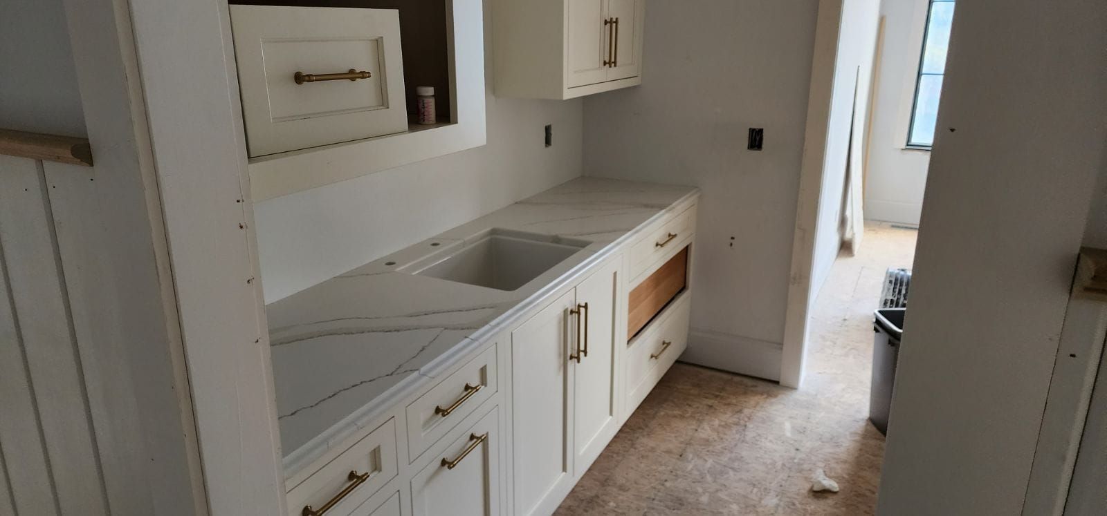White kitchen cabinets with a marble countertop and a sink.