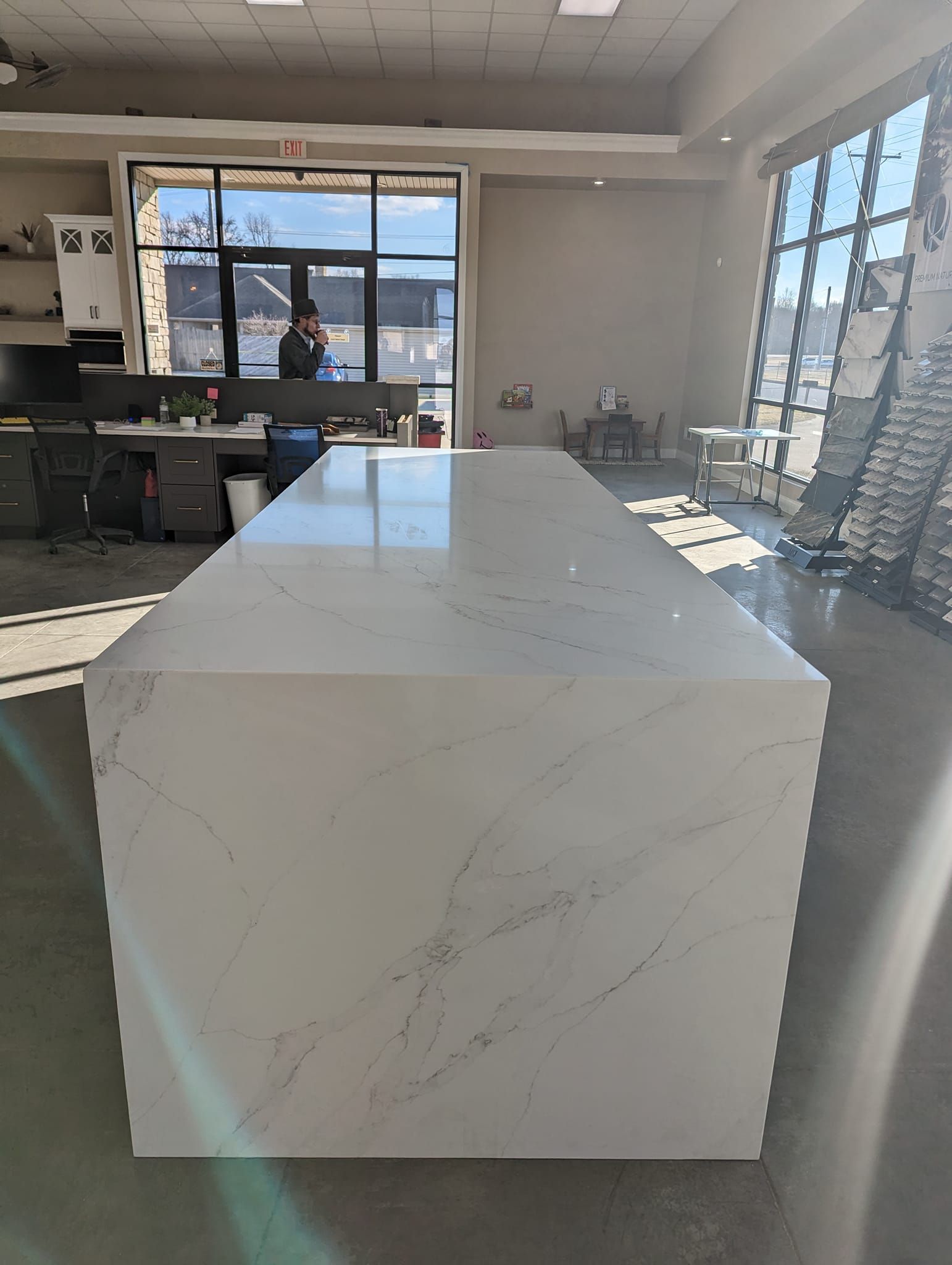 Large white marble kitchen island in a bright, open space with large windows.