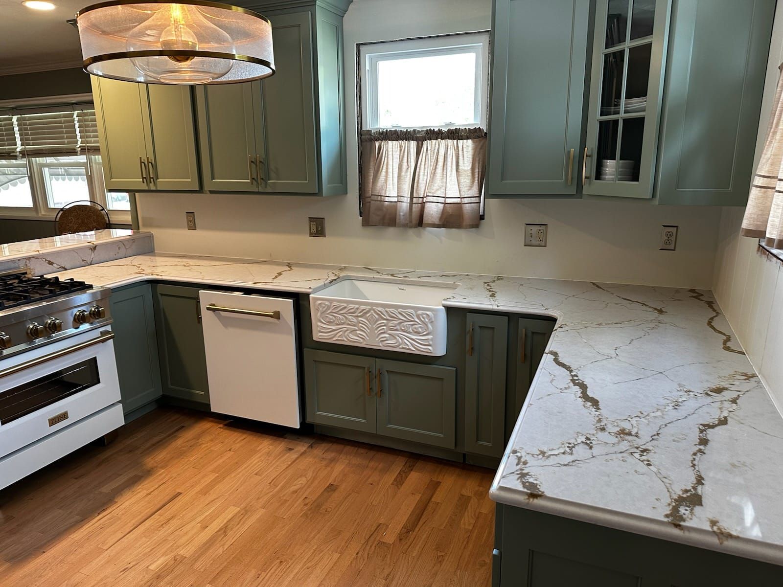 Kitchen with sage green cabinets, white countertops, and a farmhouse sink.