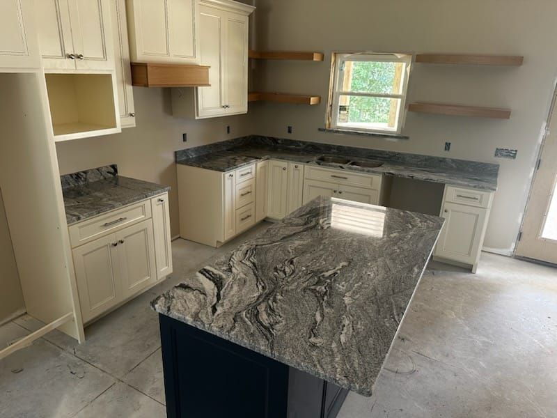 Cream kitchen with dark granite countertops, blue island, and natural light from window.