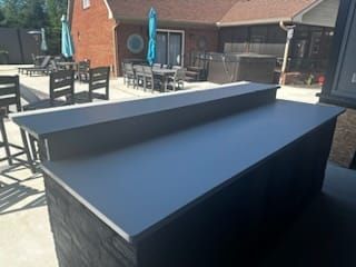 Outdoor bar with black countertop, in a backyard setting.