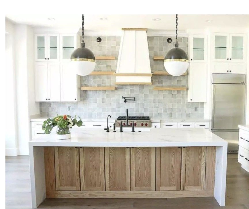 Modern kitchen with white cabinets, light wood island, marble countertops, and pendant lights.