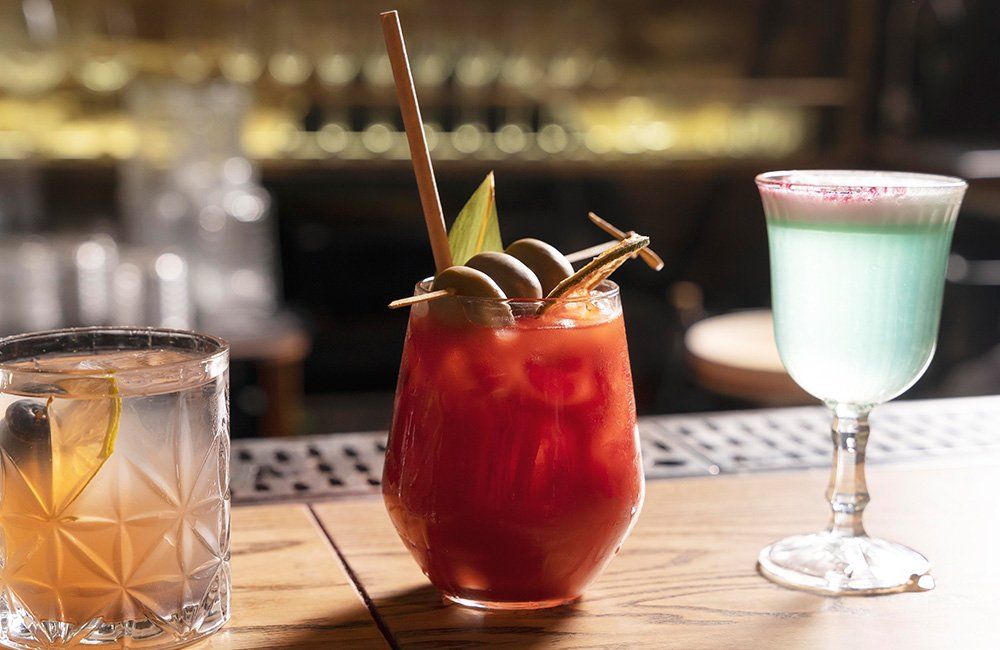 Three different types of drinks are sitting on a bar.