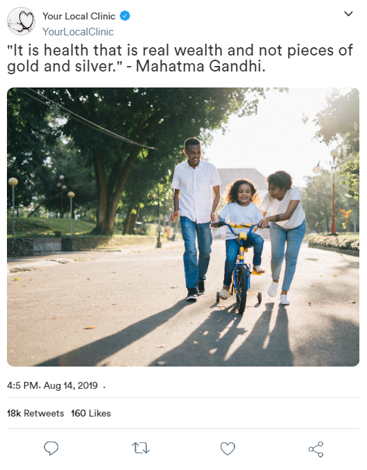 A family is riding a bike down a street with a quote from mahatma gandhi.