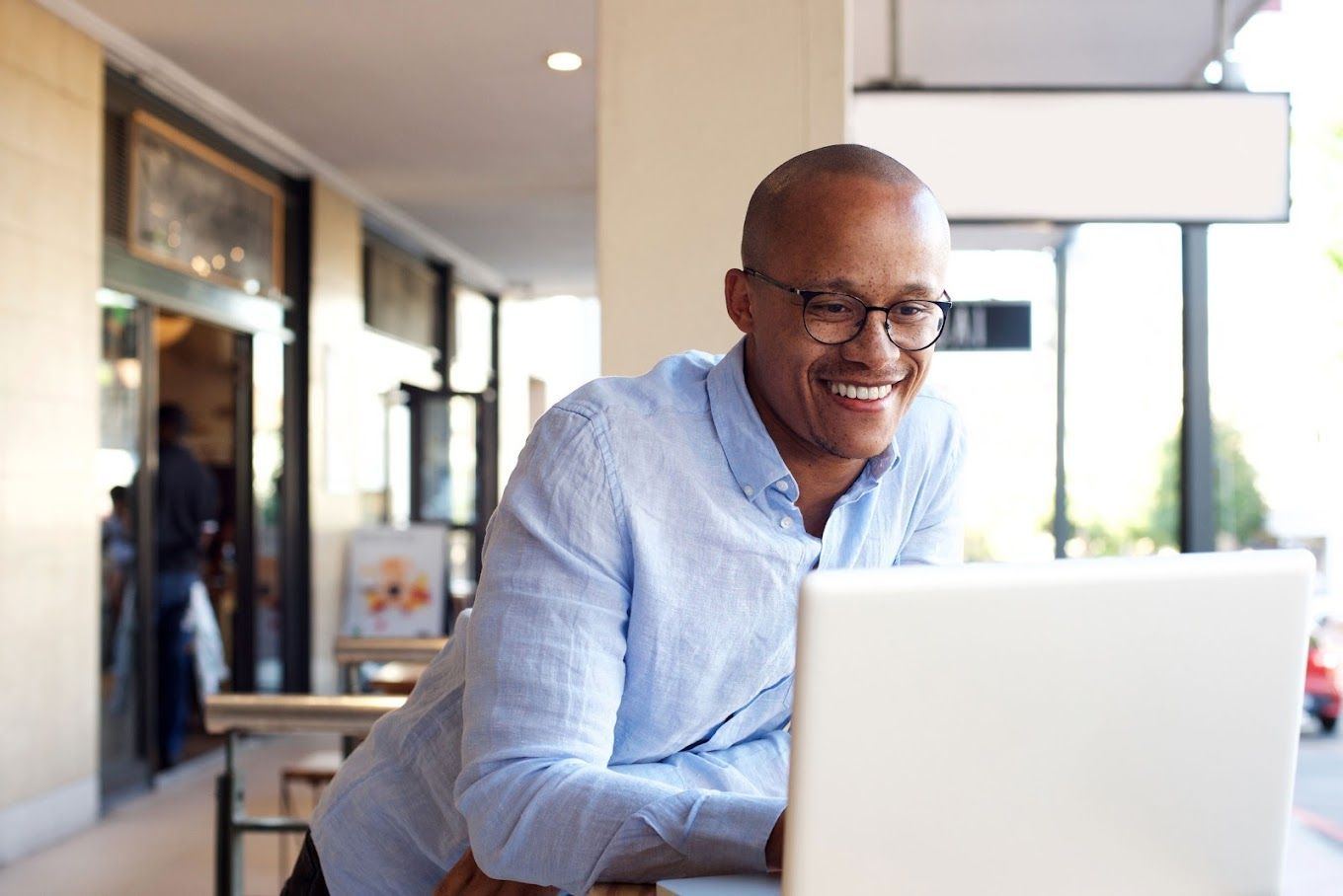 A man is sitting at a table using a laptop computer.