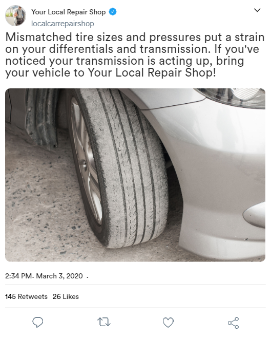 A white car with a dirty tire is sitting on the ground.