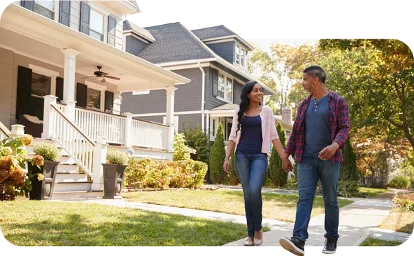 Couple walking down the sidewalk with a newly roofed home in the background, highlighting how to participate in Edge Roofing’s referral program.