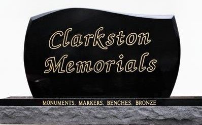 Clarkston Memorials sign with teal posts and cream lettering in front of a brick wall