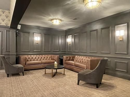 Elegant gray lounge with tufted brown sofas, armchairs, coffee table, and wall sconces