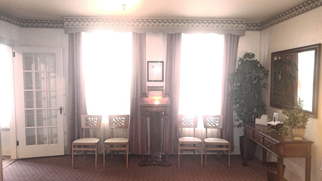 Interior of a room with natural light streaming in, including a door, windows, chairs, and a small table.