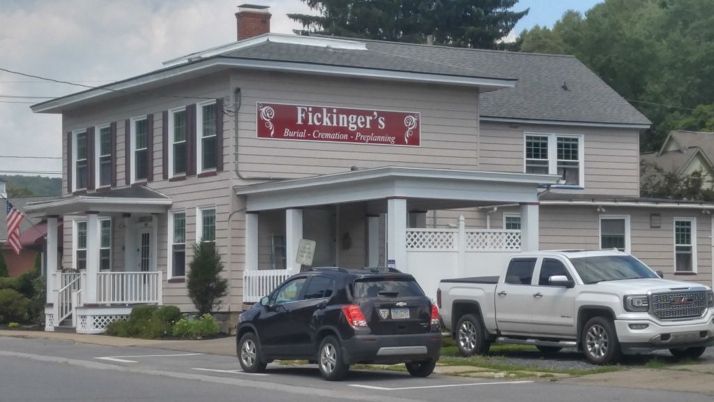 Fleming's, a business, with cars parked in front. Gray building with a red sign.