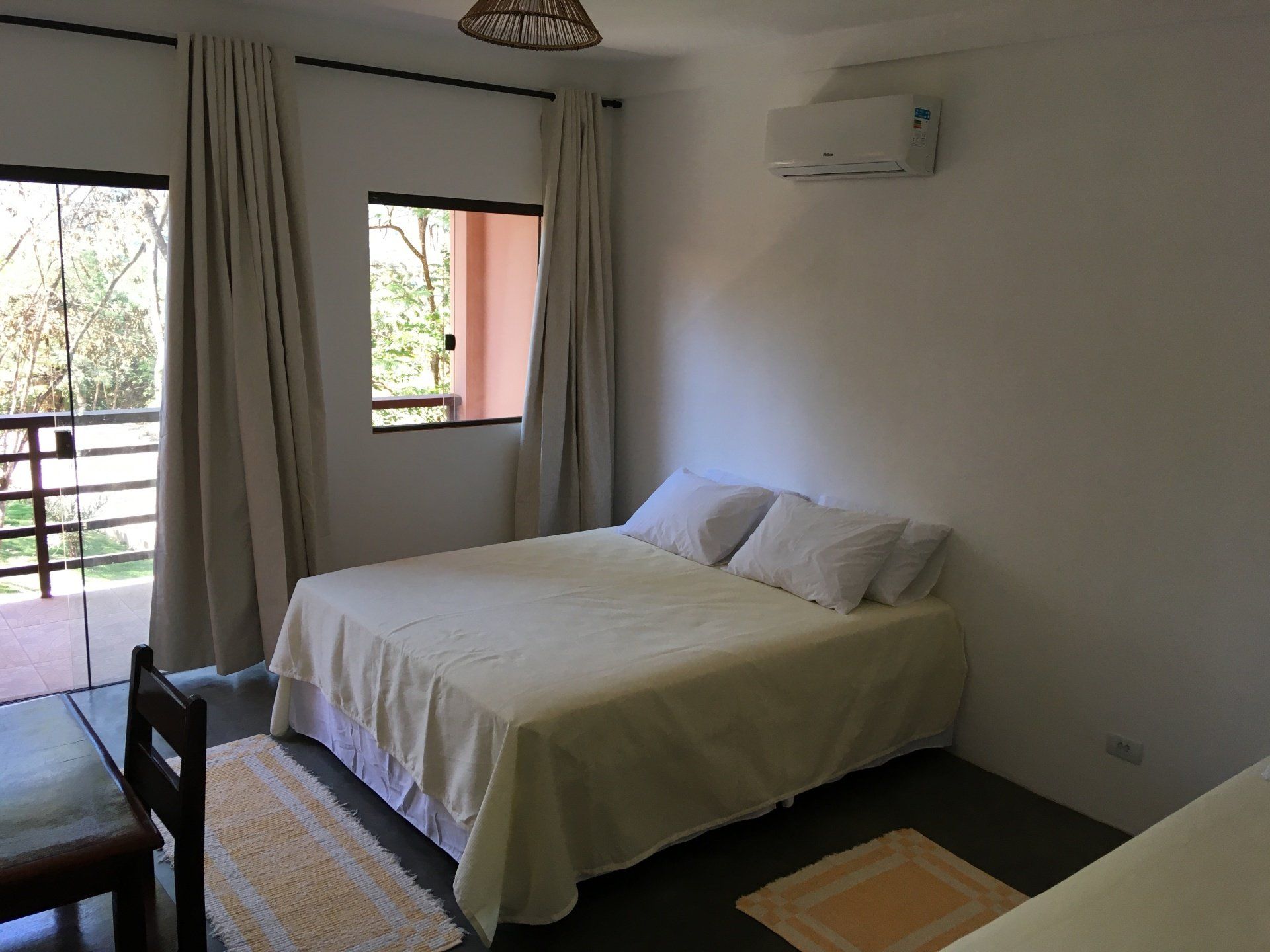 Quarto com uma cama, janelas e um pequeno tapete.