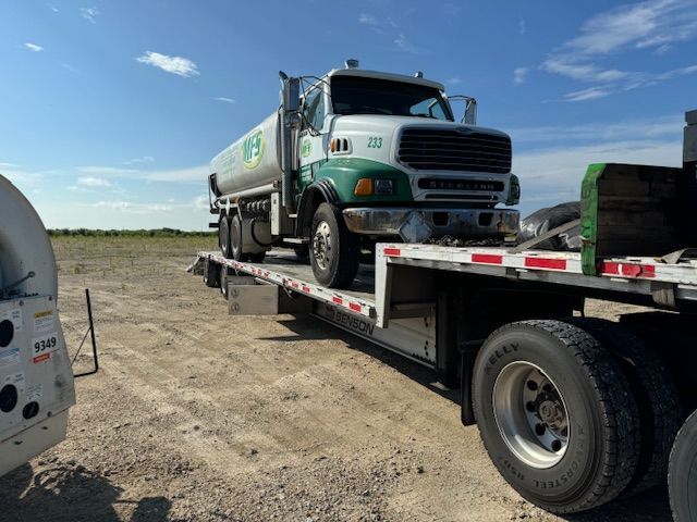 A tanker truck is sitting on top of a flatbed trailer.