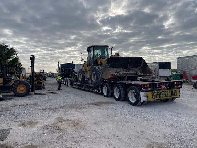 A tractor is being transported on a trailer with a sign on the back that says oversize load
