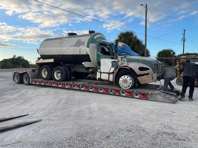 A tanker truck is sitting on top of a flatbed trailer.