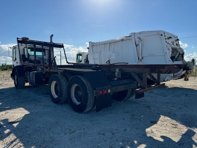A white dump truck is parked in a dirt field.