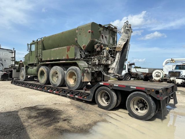 A green truck is sitting on top of a flatbed trailer.