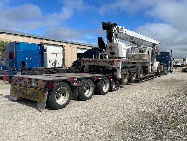 A semi truck is carrying a crane on a flatbed trailer.