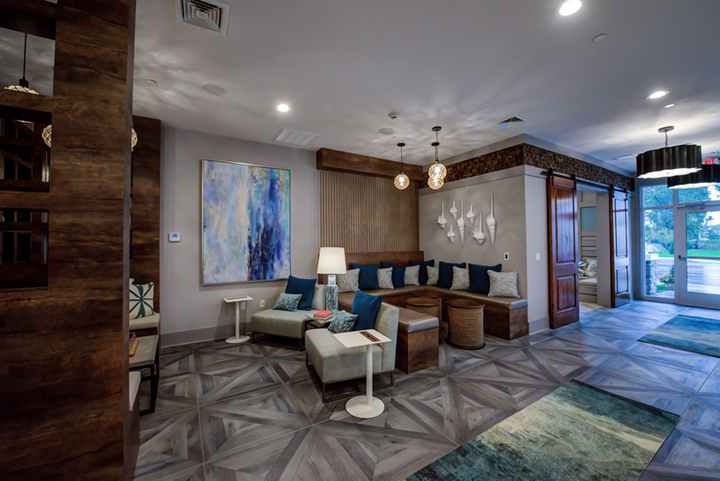 A living room with a couch , chairs , tables and a rug.