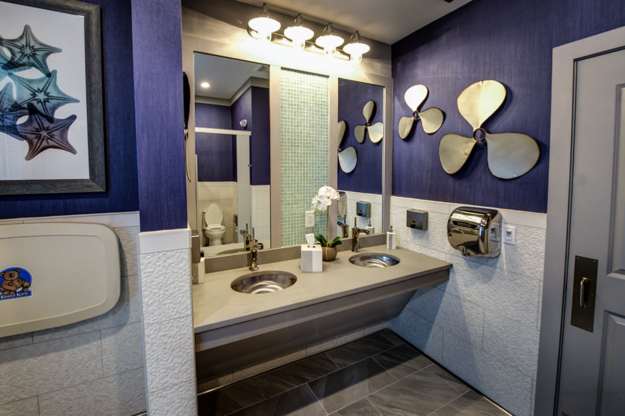 A bathroom with two sinks , a mirror and a changing table.