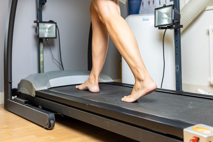 Une personne marche pieds nus sur un tapis roulant.