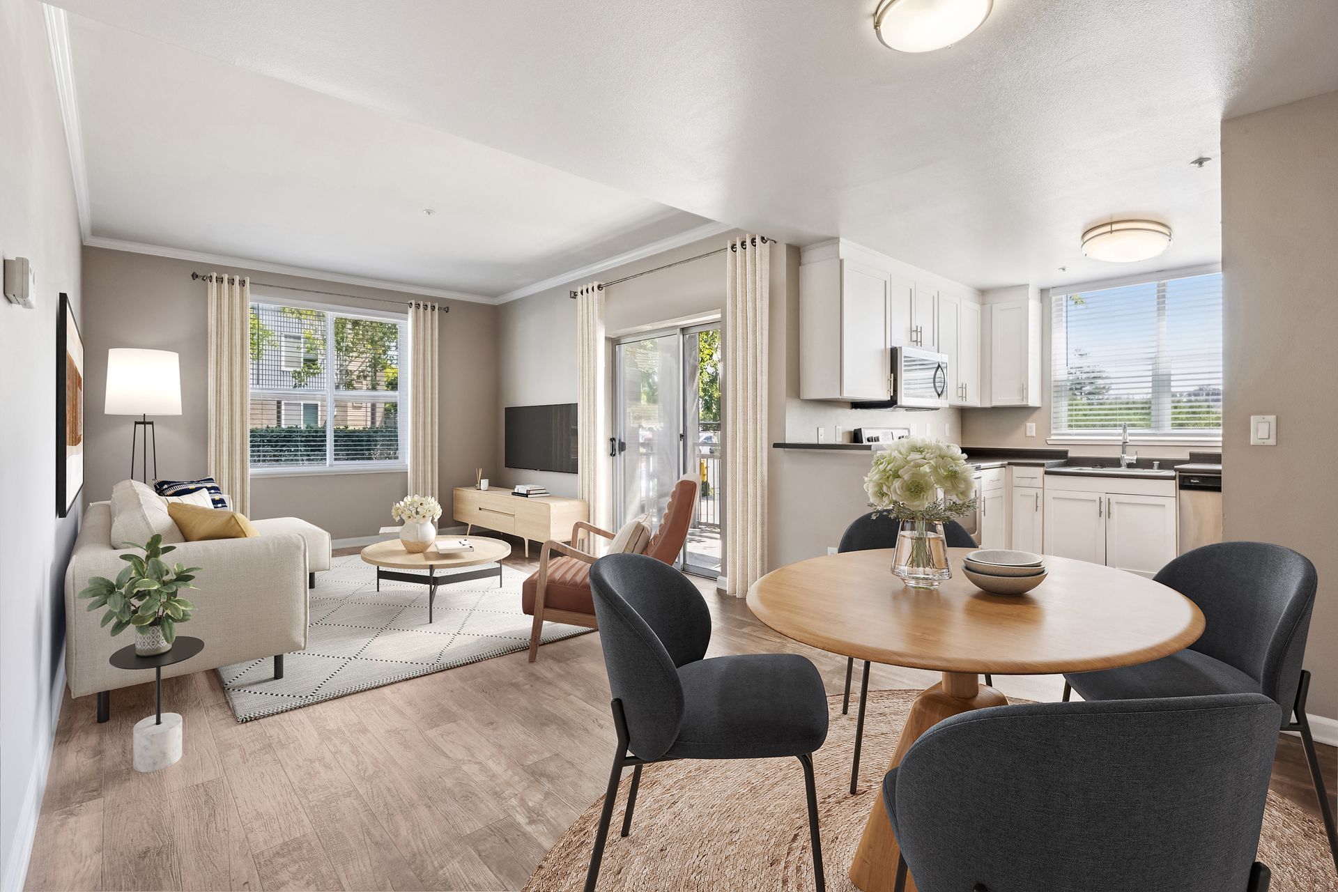 Open-concept apartment with living room, kitchen, and dining area. Neutral colors with modern furniture and a sliding door.