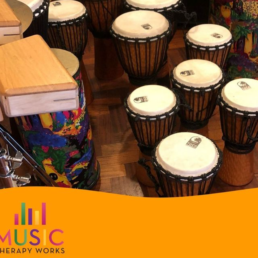 Drums of various sizes and styles, some with bright patterns, in a warm-toned room.