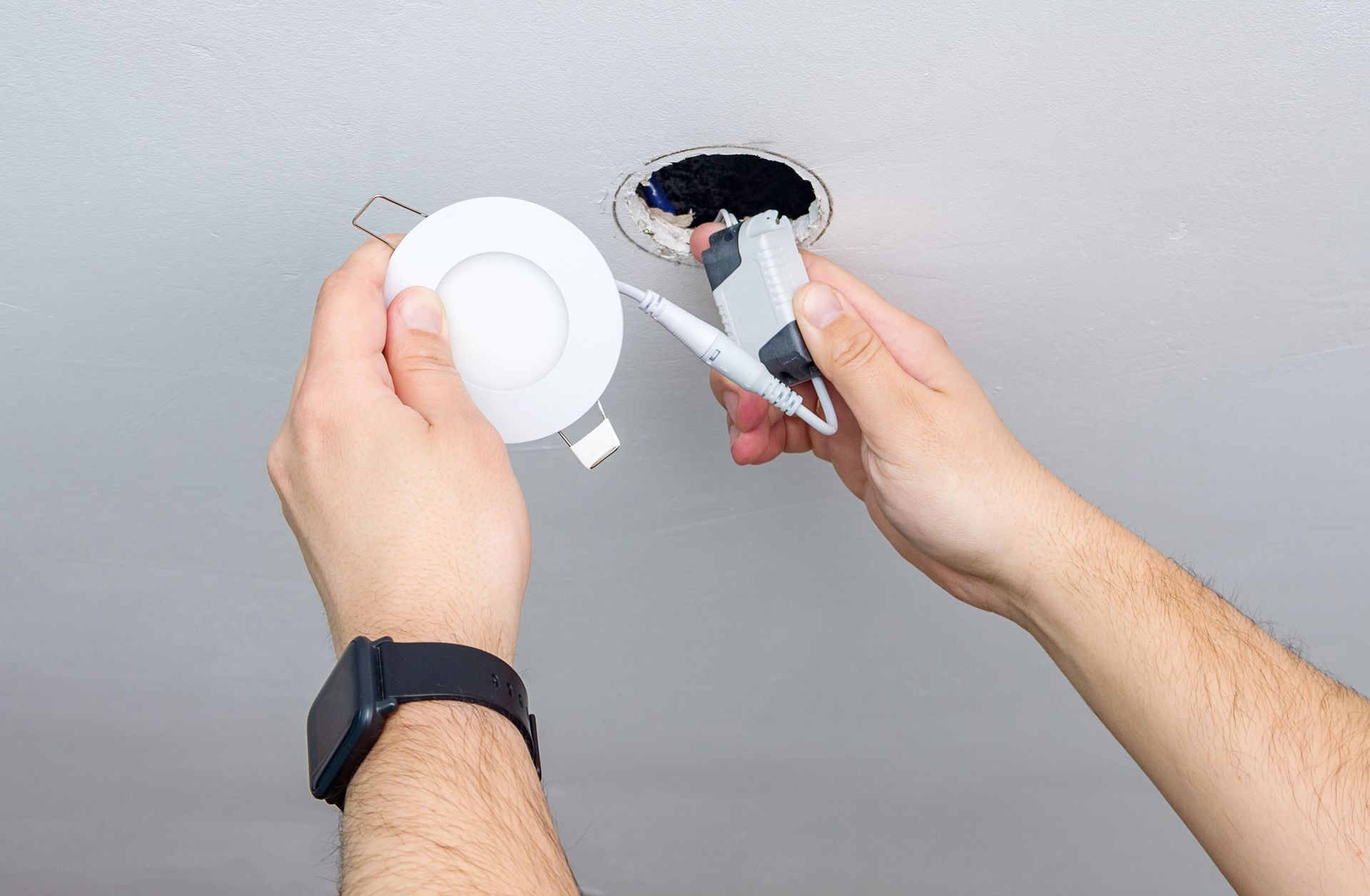 A person is installing a light fixture in the ceiling.